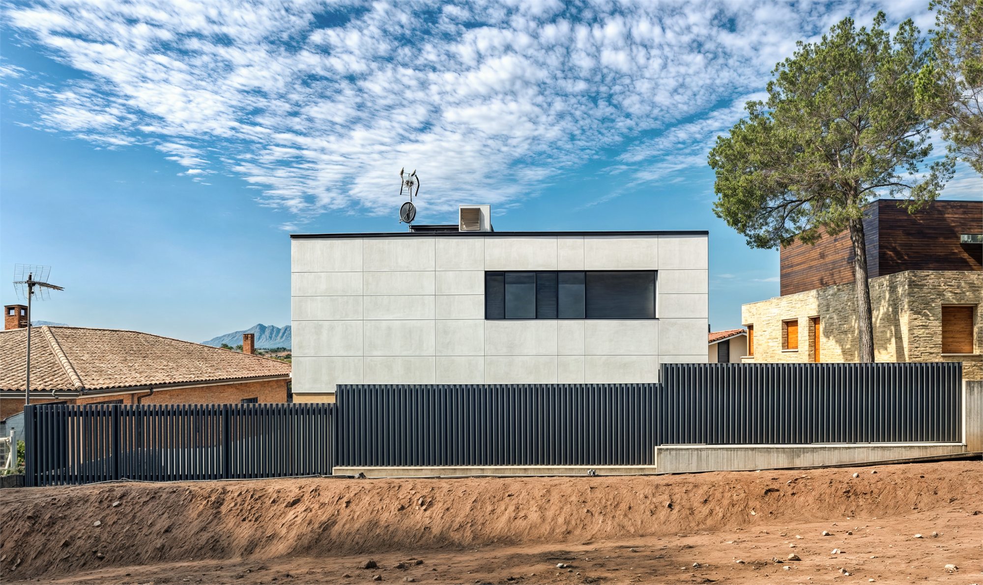 Testera cega de la casa revestida amb panell de gran format i una finestra apaïsada
