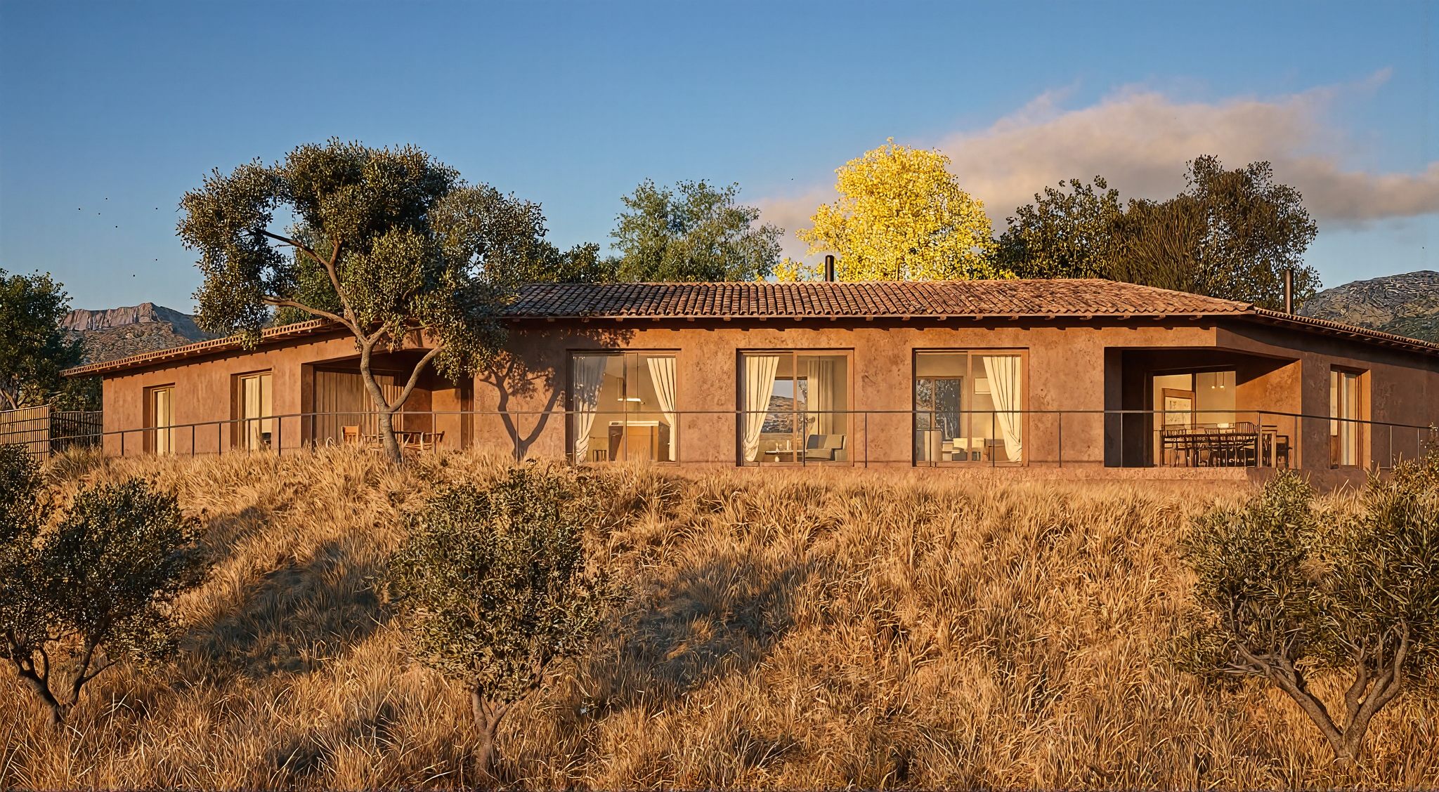 La casa vista des de l'oliverar, a última hora de la tarda: un únic volum baix de façana terracota i coberta de teula, amb les balconeres obertes al camp i els olivers al davant