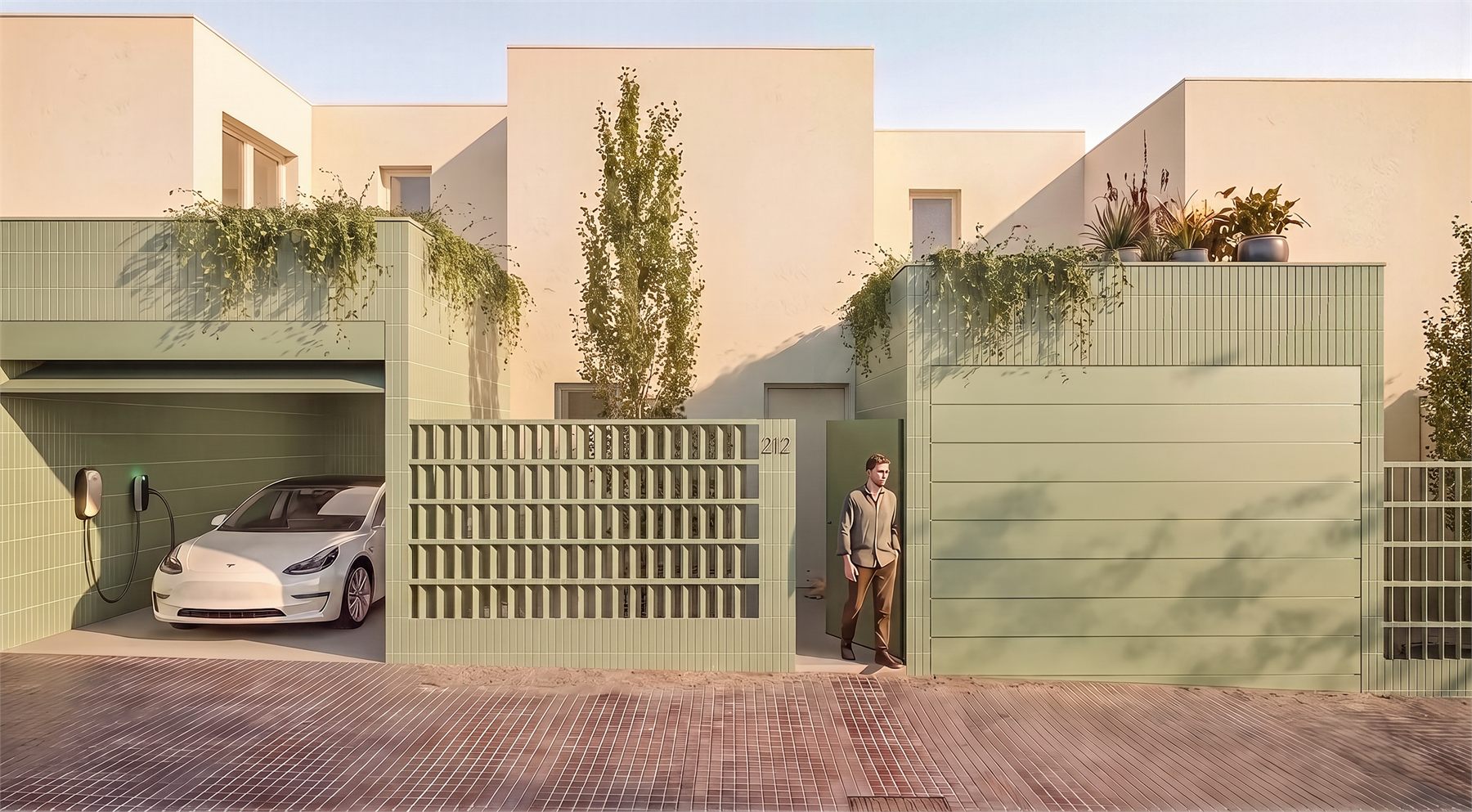 La façana al carrer d'una casa, de dia: el garatge obert amb un cotxe elèctric endollat, la gelosia de rajola verda que filtra el pati d'entrada i la porta de la casa amb el número