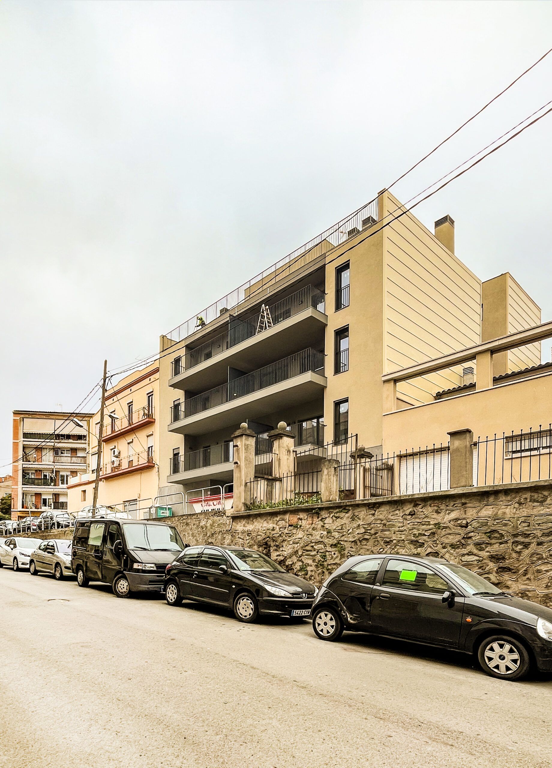 Carrer amb cotxes aparcats i edifici. Projecte de Pastor + Associates, expert en arquitectura